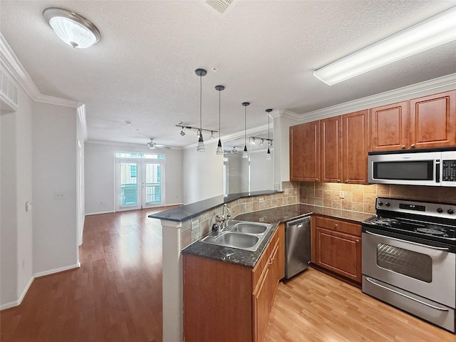 1711 Old Spanish Trl Unit 240, Houston, TX 77054 - kitchen featuring appliances with stainless steel finishes, a peninsula, brown cabinets, dark countertops, and crown molding