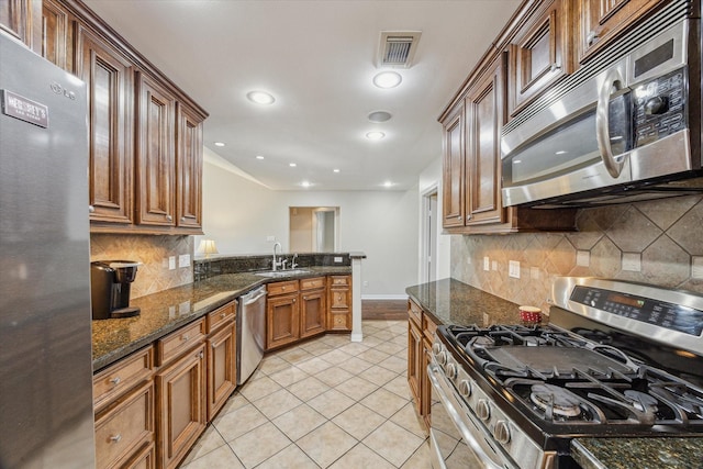 2826 Meadow Brook Ct, League City, TX 77573 - kitchen featuring stainless steel appliances, light tile patterned flooring, dark stone counters, decorative backsplash, and recessed lighting