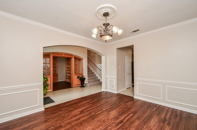 1501 Mulberry Ct, Pearland, TX 77581 - empty room featuring arched walkways, a chandelier, ornamental molding, wood finished floors, and stairway