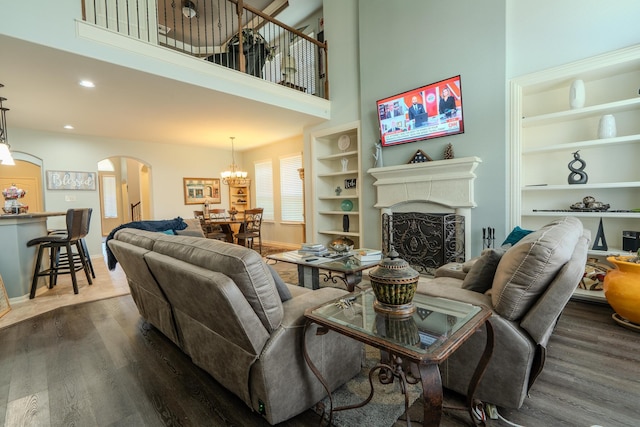 14907 Ashley Creek Ct, Humble, TX 77396 - living area with arched walkways, dark wood-style flooring, a fireplace, a towering ceiling, and built in features