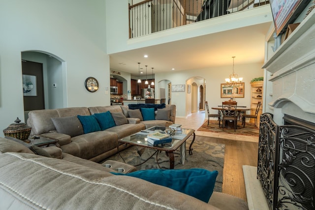 14907 Ashley Creek Ct, Humble, TX 77396 - living room with arched walkways, wood finished floors, a high ceiling, and a chandelier