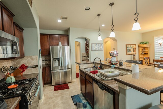14907 Ashley Creek Ct, Humble, TX 77396 - kitchen featuring appliances with stainless steel finishes, arched walkways, decorative backsplash, a large island, and hanging light fixtures