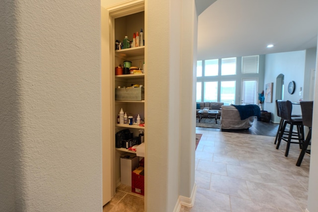 14907 Ashley Creek Ct, Humble, TX 77396 - hallway with arched walkways, a textured wall, built in shelves, light tile patterned flooring, and recessed lighting