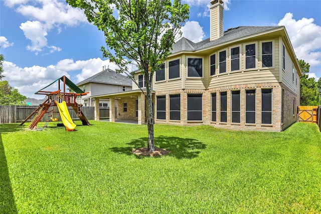 25827 Austin Spgs, Spring, TX 77373 - back of house with brick siding, a fenced backyard, a playground, and a chimney