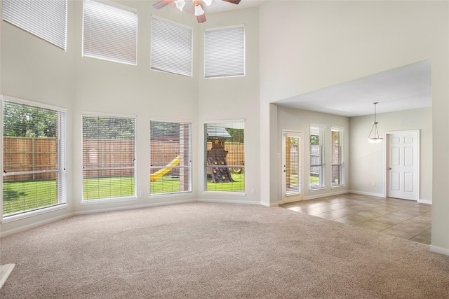 25827 Austin Spgs, Spring, TX 77373 - unfurnished living room featuring carpet flooring, a ceiling fan, a towering ceiling, and tile patterned floors