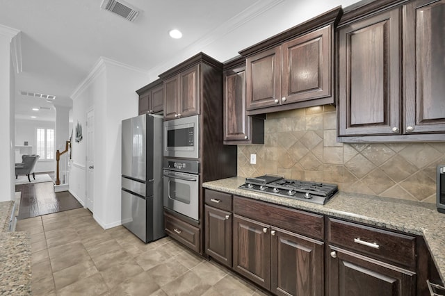 905 Wakefield Dr, Houston, TX 77018 - kitchen featuring appliances with stainless steel finishes, crown molding, dark brown cabinetry, backsplash, and light tile patterned floors