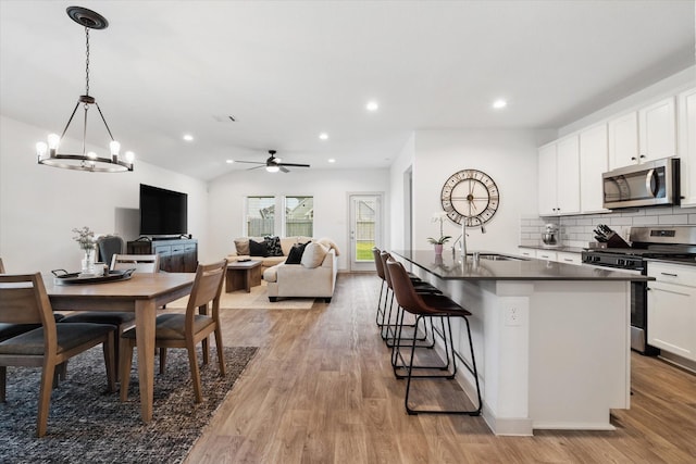 14906 Rain Tree Dr, Baytown, TX 77523 - kitchen with stainless steel appliances, dark countertops, light wood finished floors, a chandelier, and tasteful backsplash