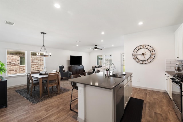 14906 Rain Tree Dr, Baytown, TX 77523 - kitchen with appliances with stainless steel finishes, dark countertops, white cabinetry, a center island with sink, and wood finished floors