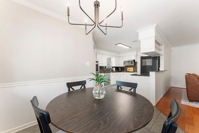 25607 Spring Ridge Dr, Spring, TX 77386 - dining space featuring a chandelier, a wainscoted wall, and crown molding