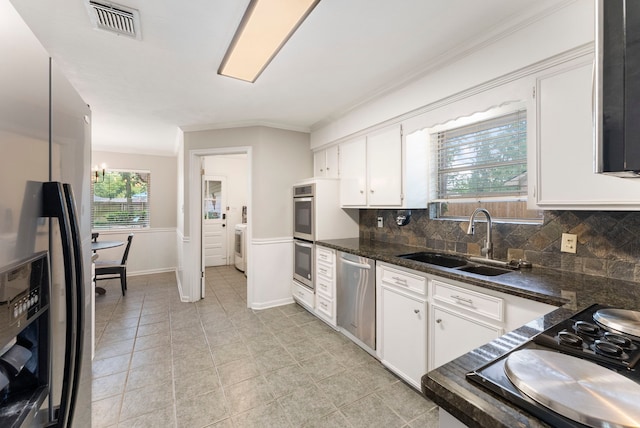 25607 Spring Ridge Dr, Spring, TX 77386 - kitchen featuring appliances with stainless steel finishes, ornamental molding, decorative backsplash, white cabinetry, and washer / dryer