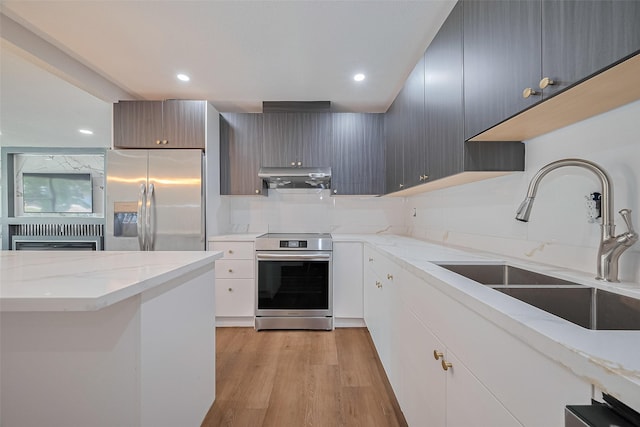 6058 Lyndhurst Dr, Houston, TX 77033 - kitchen featuring appliances with stainless steel finishes, under cabinet range hood, recessed lighting, light wood-type flooring, and light stone countertops