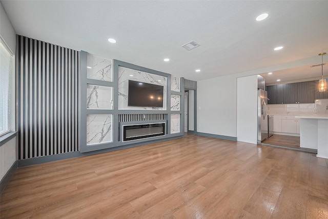 6058 Lyndhurst Dr, Houston, TX 77033 - unfurnished living room with light wood-type flooring, recessed lighting, and a fireplace