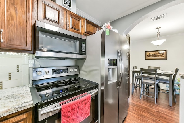 1311 Antoine Dr Unit 110, Houston, TX 77055 - kitchen featuring stainless steel appliances, crown molding, arched walkways, light wood-style flooring, and hanging light fixtures