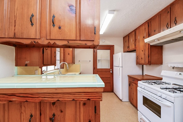1215 W 31st St, Houston, TX 77018 - kitchen with white appliances, under cabinet range hood, tile counters, brown cabinets, and a textured ceiling