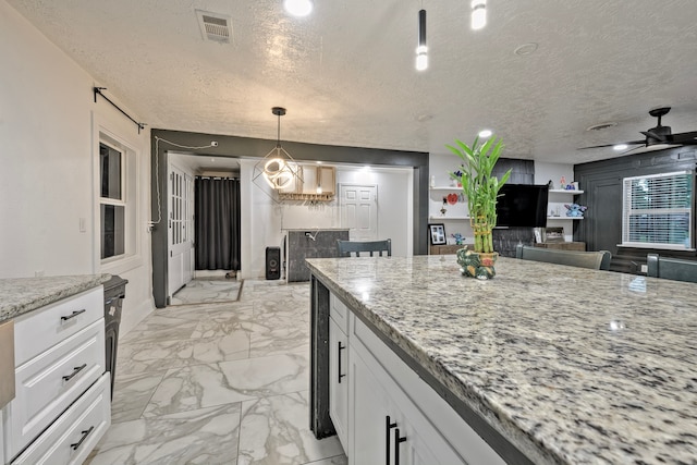 826 Rosewick St, Houston, TX 77015 - kitchen with a textured ceiling, white cabinets, light marble finish floors, light stone counters, and a ceiling fan