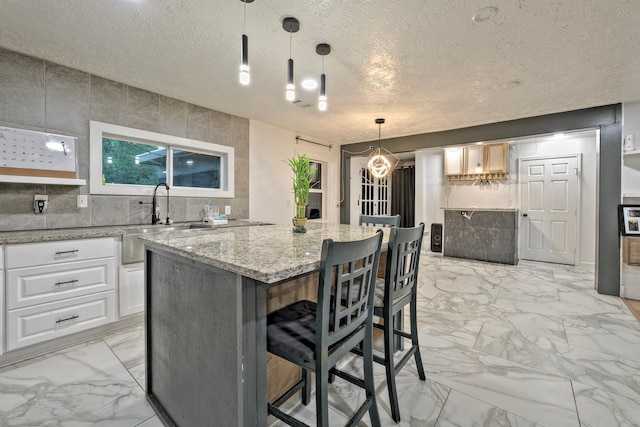 826 Rosewick St, Houston, TX 77015 - kitchen with light marble finish flooring, a textured ceiling, a kitchen island, light stone counters, and white cabinetry