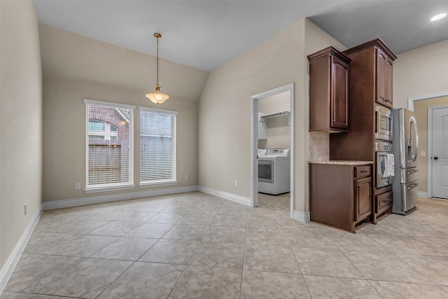 2206 Chelsea Creek Ln, Spring, TX 77386 - kitchen featuring appliances with stainless steel finishes, washer and dryer, light tile patterned flooring, decorative light fixtures, and lofted ceiling