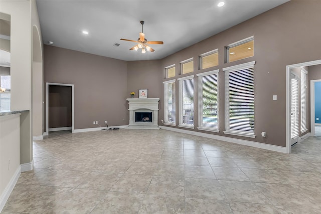 2206 Chelsea Creek Ln, Spring, TX 77386 - unfurnished living room featuring a ceiling fan, a fireplace with raised hearth, light tile patterned flooring, recessed lighting, and a high ceiling
