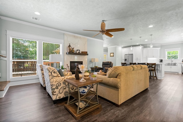 2318 Pleasant Crk, Houston, TX 77345 - living room with a textured ceiling, dark wood finished floors, crown molding, ceiling fan, and a high end fireplace