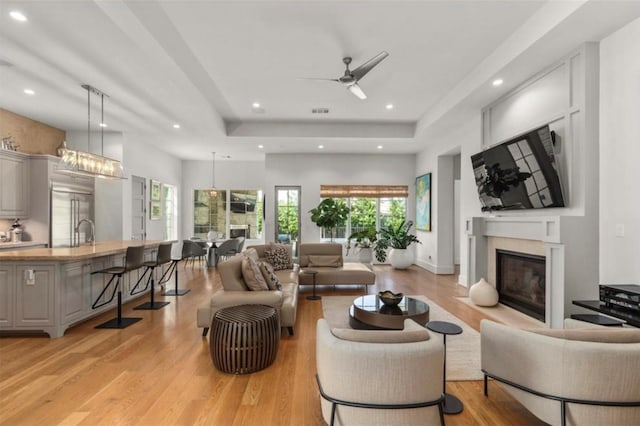 7526 Janak Dr, Houston, TX 77055 - living area featuring a glass covered fireplace, a tray ceiling, light wood finished floors, healthy amount of natural light, and recessed lighting