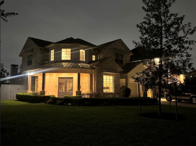 7526 Janak Dr, Houston, TX 77055 - view of front facade featuring a standing seam roof, stone siding, a lawn, a metal roof, and french doors
