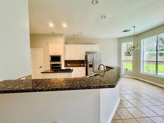 5403 Emerald Pointe Ln, Sugar Land, TX 77479 - kitchen with stainless steel appliances, light tile patterned floors, a chandelier, white cabinets, and backsplash
