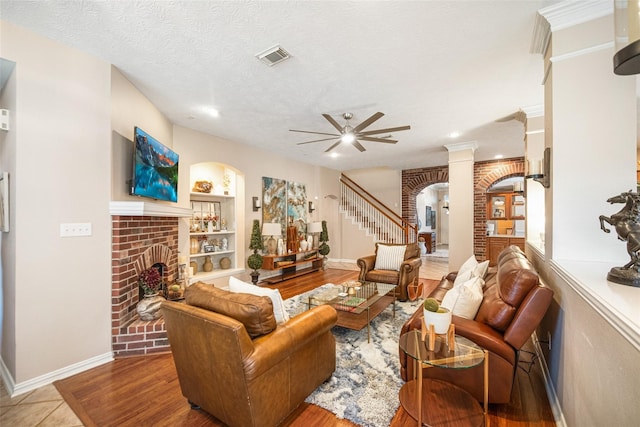 23702 Whispering Wind, Katy, TX 77494 - living room featuring a brick fireplace, a ceiling fan, arched walkways, built in shelves, and stairs
