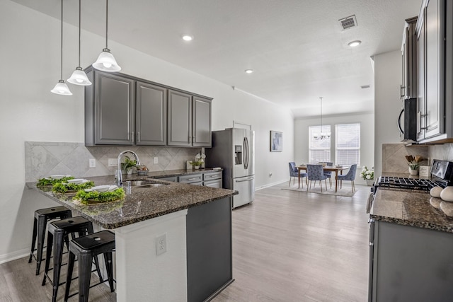 16070 Deer Pines Dr, Conroe, TX 77303 - kitchen with appliances with stainless steel finishes, light wood finished floors, dark stone countertops, tasteful backsplash, and a peninsula