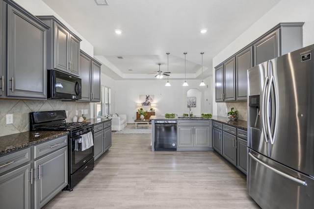 16070 Deer Pines Dr, Conroe, TX 77303 - kitchen with black appliances, a ceiling fan, gray cabinets, a tray ceiling, and light wood-type flooring