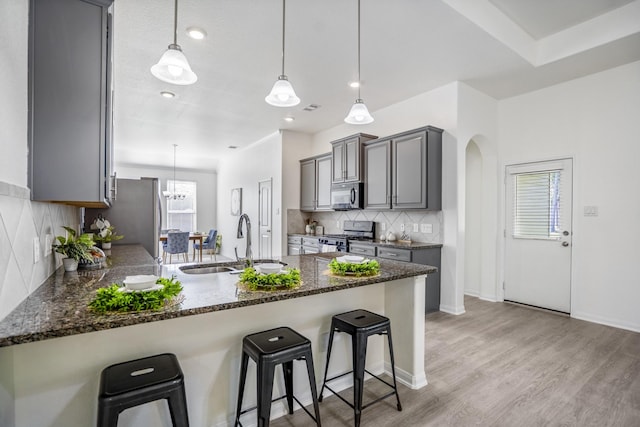16070 Deer Pines Dr, Conroe, TX 77303 - kitchen with appliances with stainless steel finishes, gray cabinetry, a peninsula, backsplash, and arched walkways