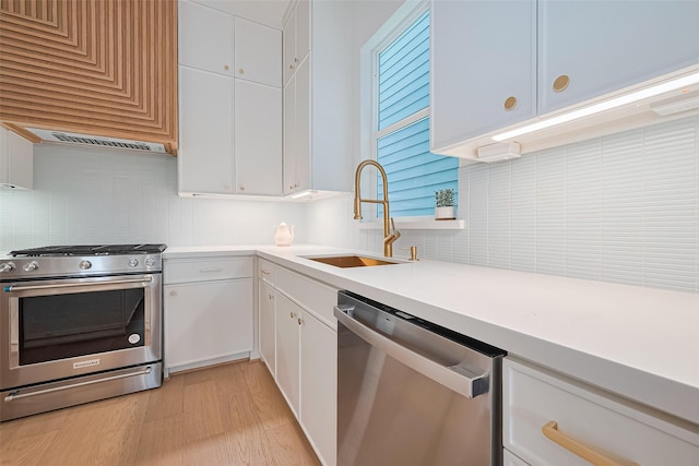 4109 Castor St Unit B, Houston, TX 77022 - kitchen with appliances with stainless steel finishes, tasteful backsplash, light countertops, white cabinets, and light wood-type flooring