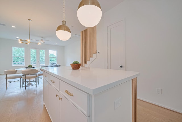 4109 Castor St Unit B, Houston, TX 77022 - kitchen featuring light wood-type flooring, ceiling fan, white cabinetry, a kitchen island, and hanging light fixtures