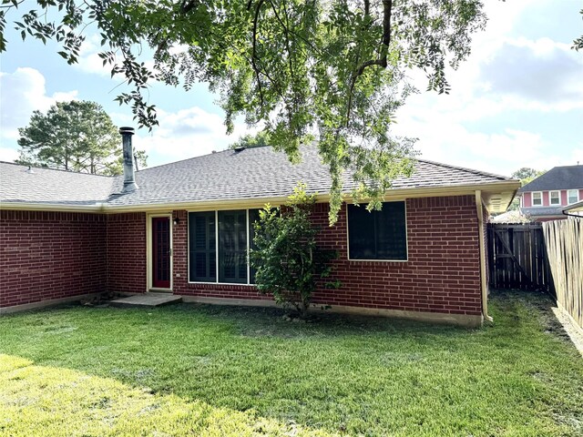 10934 Covered Bridge St, Houston, TX 77075 - back of house with a fenced backyard, a shingled roof, and brick siding