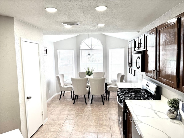 10934 Covered Bridge St, Houston, TX 77075 - kitchen featuring gas range, lofted ceiling, dark brown cabinetry, light stone counters, and light tile patterned flooring