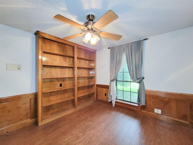 3 Thunderbird Cir, Baytown, TX 77521 - empty room featuring a textured ceiling, wood finished floors, a wainscoted wall, and a ceiling fan