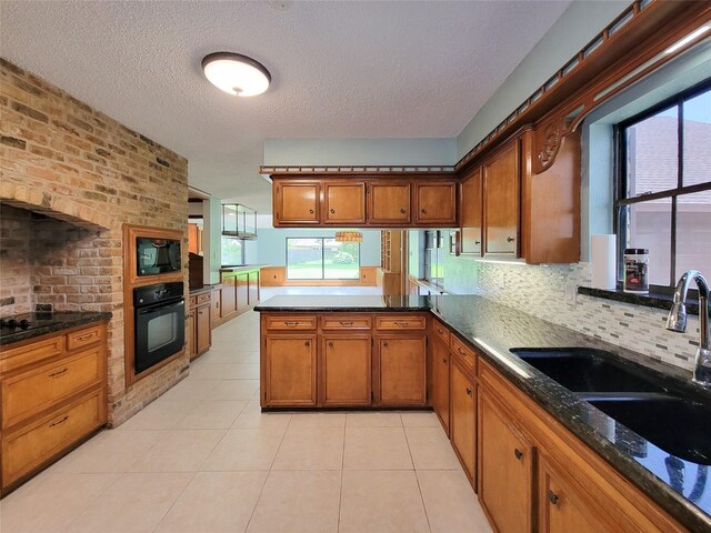 3 Thunderbird Cir, Baytown, TX 77521 - kitchen with black appliances, brown cabinetry, a peninsula, a textured ceiling, and plenty of natural light