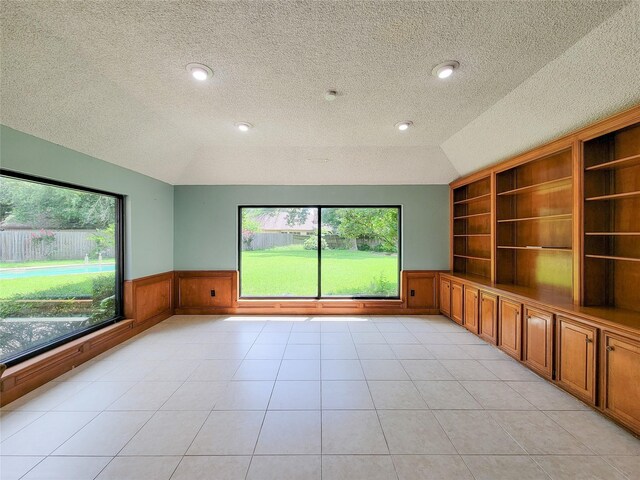 3 Thunderbird Cir, Baytown, TX 77521 - empty room featuring vaulted ceiling, wainscoting, a textured ceiling, built in features, and light tile patterned floors