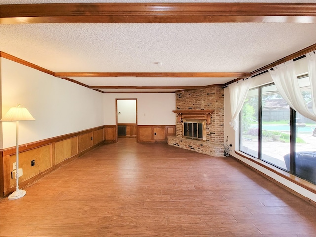 3 Thunderbird Cir, Baytown, TX 77521 - unfurnished living room featuring wainscoting, light wood-type flooring, a brick fireplace, a textured ceiling, and beam ceiling