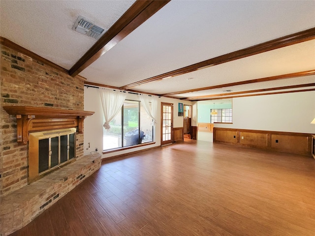 3 Thunderbird Cir, Baytown, TX 77521 - unfurnished living room featuring beam ceiling, a fireplace, wood finished floors, a wainscoted wall, and a textured ceiling