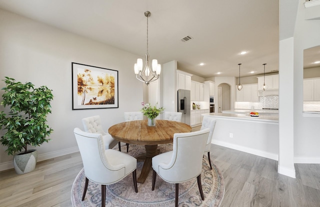 12611 Faded Sky Ct, Cypress, TX 77433 - dining area with light wood-style flooring, arched walkways, recessed lighting, and a chandelier