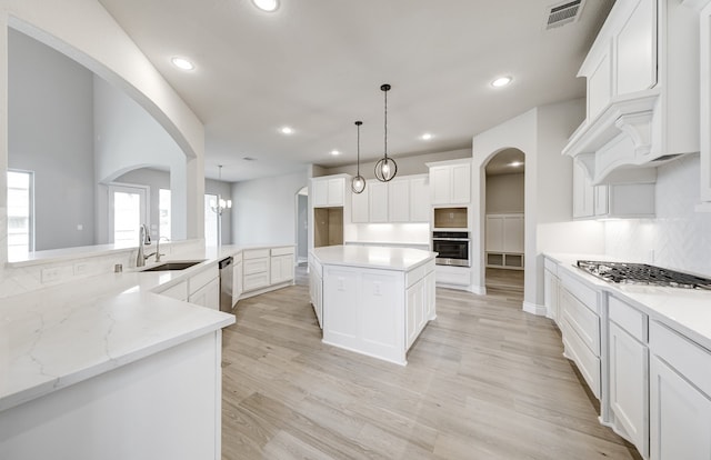 12611 Faded Sky Ct, Cypress, TX 77433 - kitchen featuring stainless steel appliances, arched walkways, recessed lighting, light wood-style flooring, and white cabinets