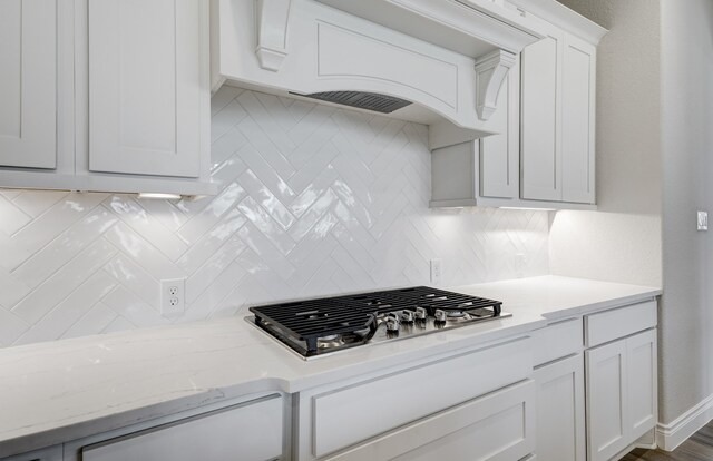12611 Faded Sky Ct, Cypress, TX 77433 - kitchen with stainless steel gas cooktop, backsplash, white cabinets, and light stone counters
