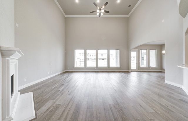 12611 Faded Sky Ct, Cypress, TX 77433 - unfurnished living room with a ceiling fan, a fireplace with raised hearth, light wood-type flooring, crown molding, and a high ceiling