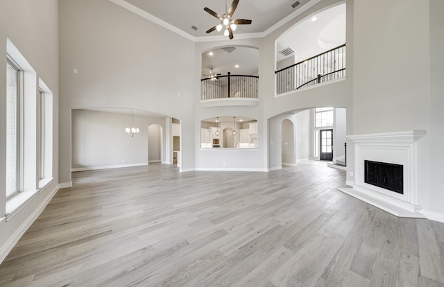 12611 Faded Sky Ct, Cypress, TX 77433 - unfurnished living room featuring a ceiling fan, a fireplace with raised hearth, arched walkways, a chandelier, and light wood-style flooring