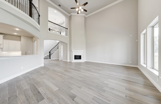 12611 Faded Sky Ct, Cypress, TX 77433 - unfurnished living room with a ceiling fan, a high ceiling, arched walkways, stairway, and a fireplace