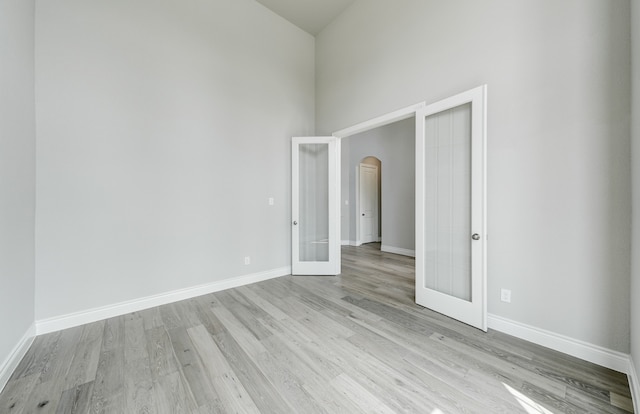 12611 Faded Sky Ct, Cypress, TX 77433 - spare room featuring arched walkways, french doors, high vaulted ceiling, and light wood finished floors