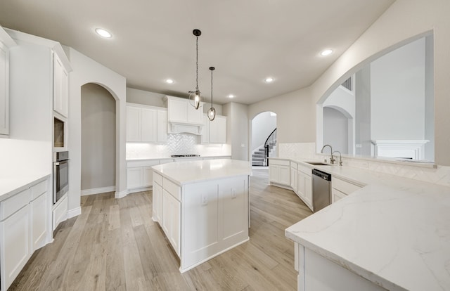 12611 Faded Sky Ct, Cypress, TX 77433 - kitchen with appliances with stainless steel finishes, light wood finished floors, backsplash, a center island, and white cabinets