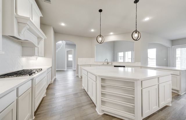 12611 Faded Sky Ct, Cypress, TX 77433 - kitchen featuring arched walkways, stainless steel gas cooktop, a kitchen island, recessed lighting, and backsplash