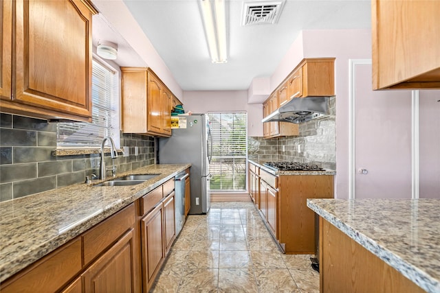 726 Park Knoll Ln, Katy, TX 77450 - kitchen featuring appliances with stainless steel finishes, under cabinet range hood, light stone counters, decorative backsplash, and brown cabinets