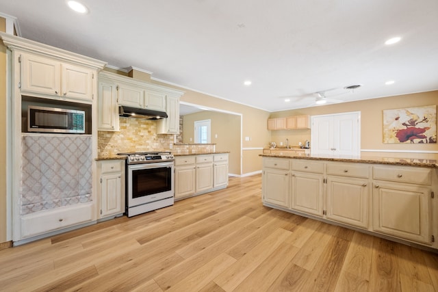 5254 State Highway 146 S, Livingston, TX 77351 - kitchen with appliances with stainless steel finishes, under cabinet range hood, light wood-style floors, backsplash, and light stone countertops